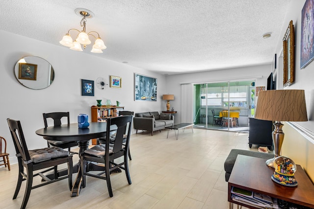 dining area featuring light wood-style flooring, a textured ceiling, and a notable chandelier