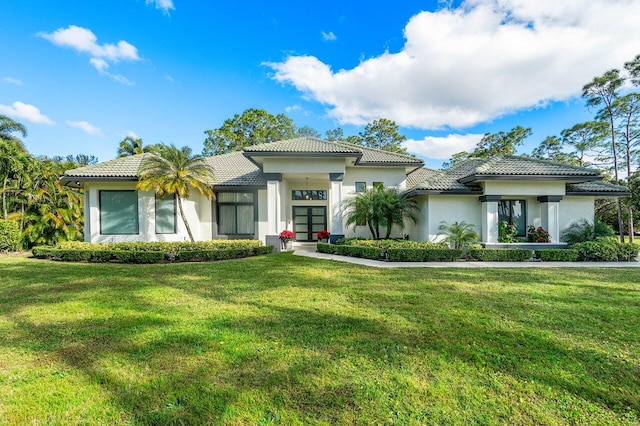 view of front of property featuring stucco siding, a tiled roof, and a front yard