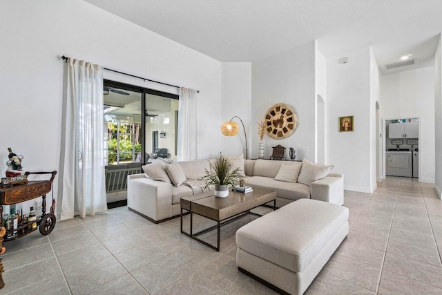 living room with arched walkways, visible vents, light tile patterned flooring, and separate washer and dryer