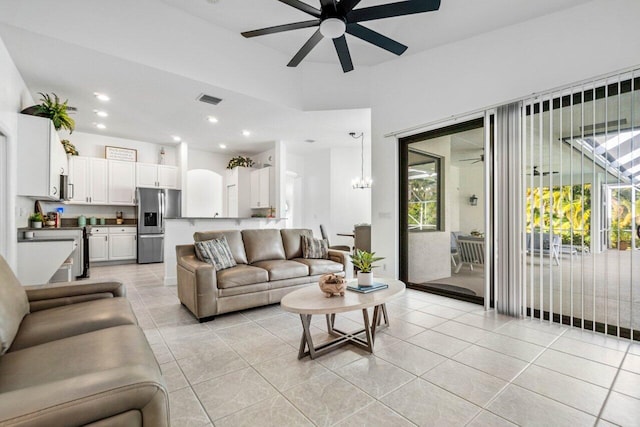 living room featuring ceiling fan with notable chandelier, visible vents, plenty of natural light, and light tile patterned floors