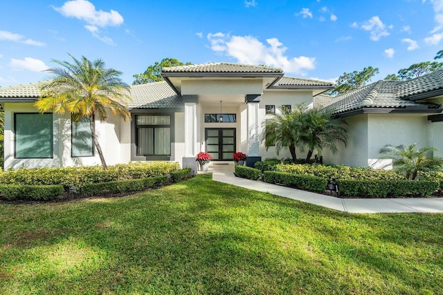 view of front of home with stucco siding, a tiled roof, and a front yard