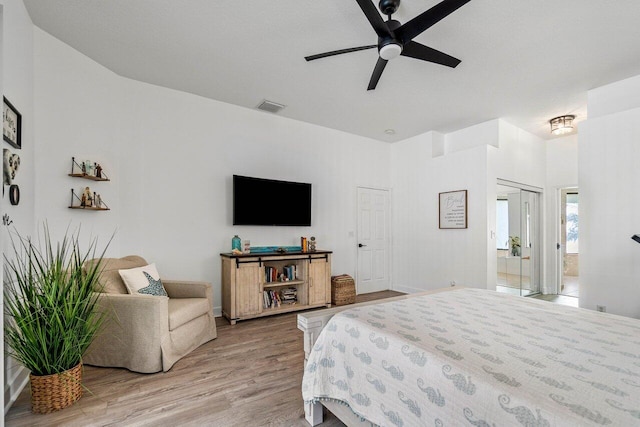 bedroom with visible vents, a high ceiling, light wood-style floors, connected bathroom, and ceiling fan