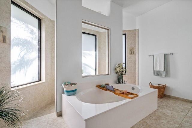 full bath featuring a garden tub, baseboards, and tile patterned floors