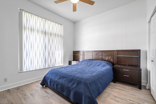 bedroom with ceiling fan, light wood finished floors, multiple windows, and baseboards