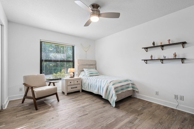 bedroom featuring light wood-style floors, ceiling fan, a textured ceiling, and baseboards