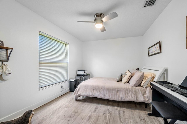 bedroom with light wood finished floors, baseboards, visible vents, and a ceiling fan