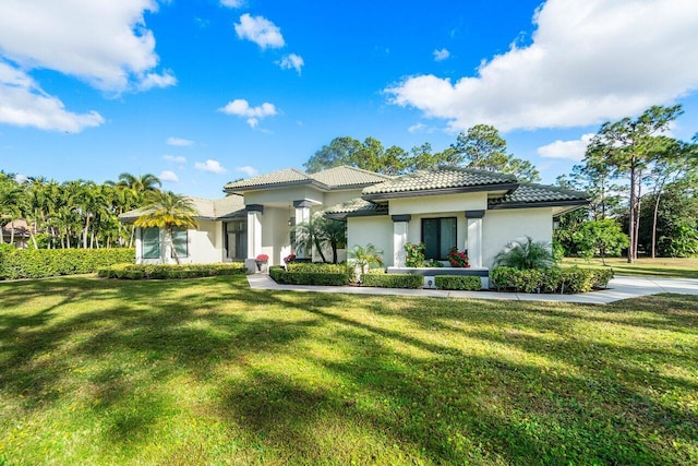 view of front of property with stucco siding, a tile roof, and a front yard