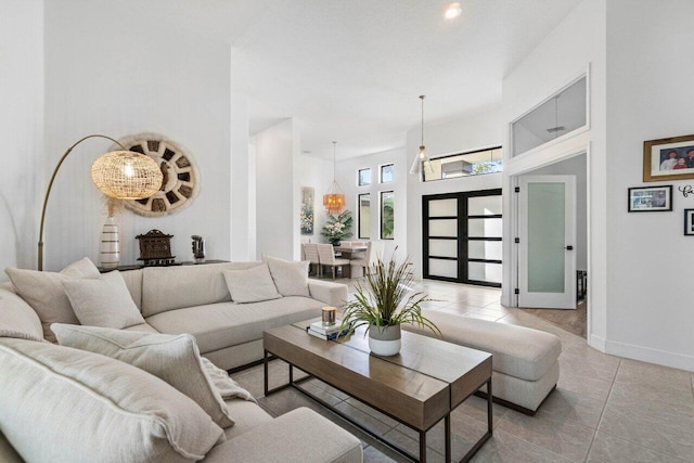 living room with light tile patterned floors, a high ceiling, and baseboards