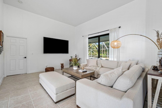 living area featuring high vaulted ceiling, baseboards, and light tile patterned floors