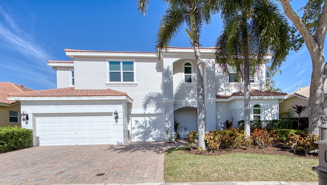 mediterranean / spanish home featuring stucco siding, a tiled roof, and decorative driveway