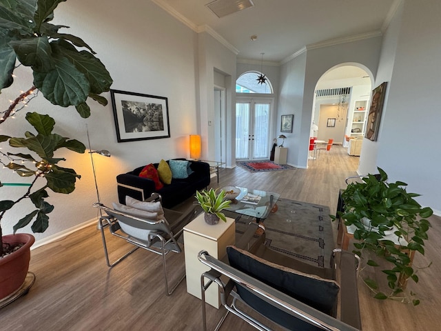 interior space with arched walkways, french doors, ornamental molding, wood finished floors, and baseboards