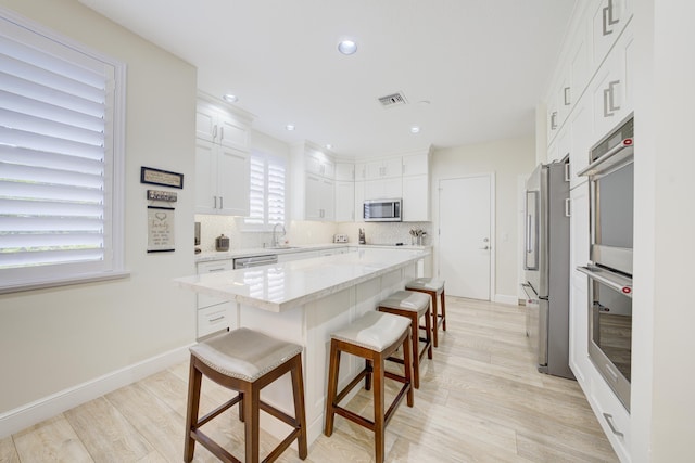 kitchen featuring stainless steel appliances, white cabinetry, a kitchen island, and a sink