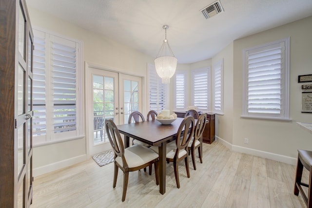 dining space featuring light wood-style floors, baseboards, visible vents, and french doors