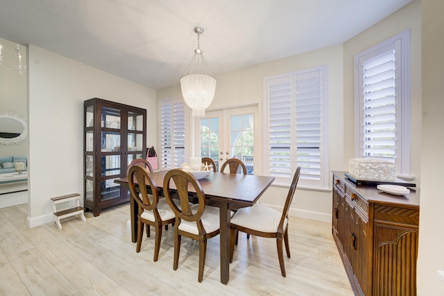 dining space with a chandelier, light wood-type flooring, french doors, and baseboards