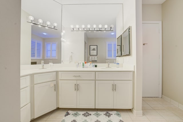 full bath featuring double vanity, baseboards, a sink, and tile patterned floors