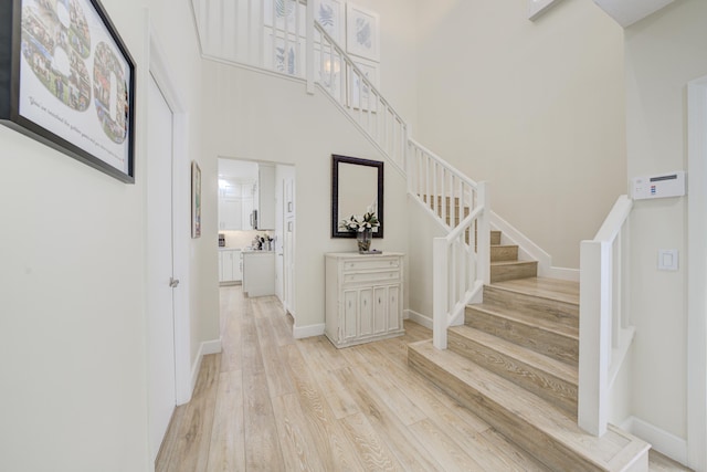 stairs with a towering ceiling, baseboards, and wood finished floors