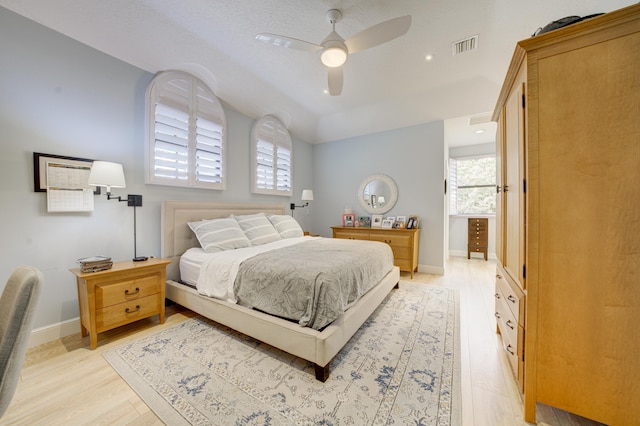 bedroom with light wood-style floors, visible vents, baseboards, and a ceiling fan