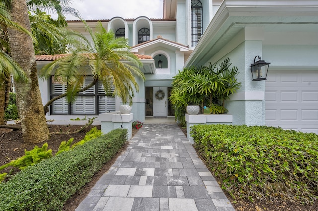 entrance to property featuring a garage and stucco siding