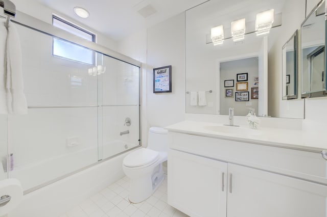 full bath featuring bath / shower combo with glass door, tile patterned flooring, vanity, and toilet