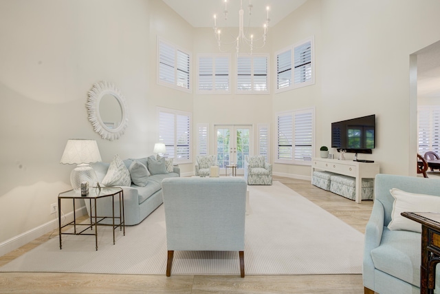 living room featuring light wood-style flooring, baseboards, a notable chandelier, and french doors