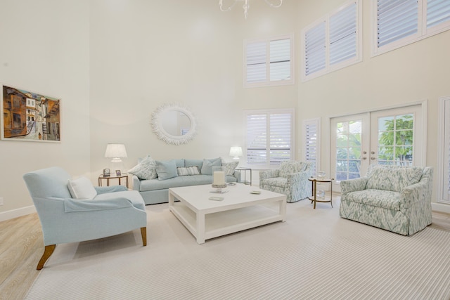 living area featuring french doors, wood finished floors, a towering ceiling, and baseboards