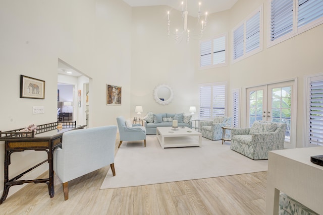 living area with light wood-type flooring, french doors, and a notable chandelier