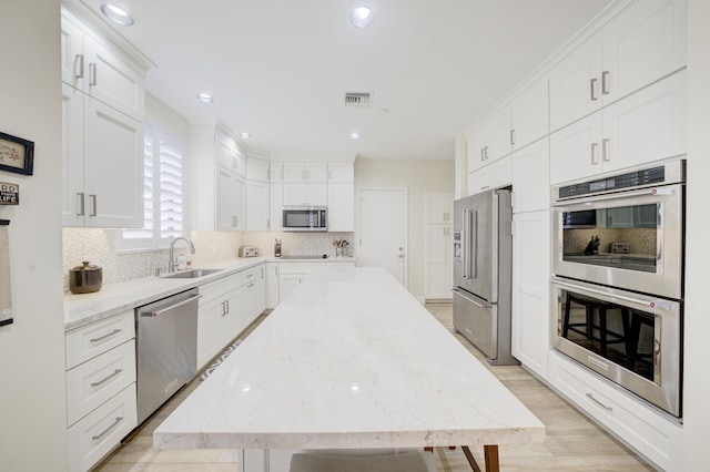 kitchen with appliances with stainless steel finishes, a sink, and white cabinets