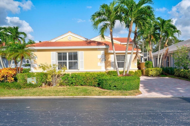 view of front facade with a tile roof, decorative driveway, and stucco siding