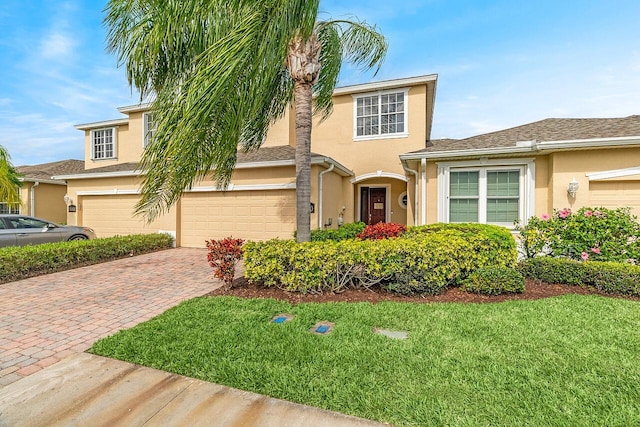 view of front of home with a garage, a front yard, decorative driveway, and stucco siding