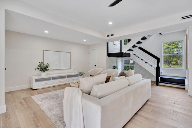 living room with light wood-type flooring, stairs, baseboards, and recessed lighting