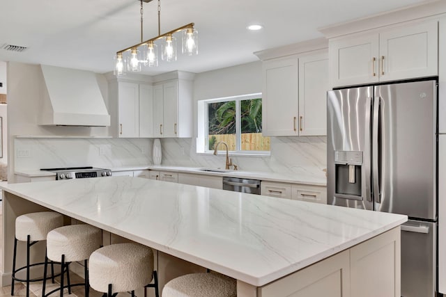 kitchen featuring white cabinets, custom range hood, a kitchen island, and stainless steel appliances