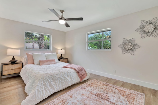 bedroom featuring light wood-style floors, multiple windows, baseboards, and a ceiling fan