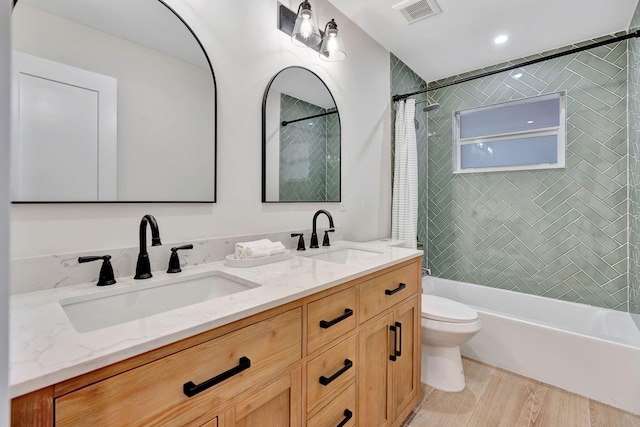 bathroom with visible vents, a sink, toilet, and double vanity