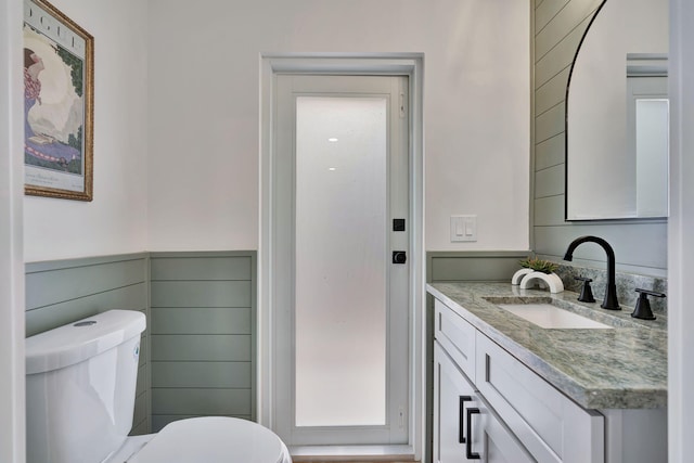 bathroom with wainscoting, vanity, and toilet