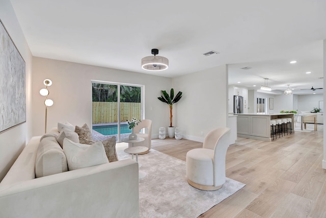 living area with light wood-style flooring, recessed lighting, visible vents, and baseboards