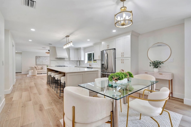 dining space with light wood finished floors, recessed lighting, visible vents, an inviting chandelier, and baseboards