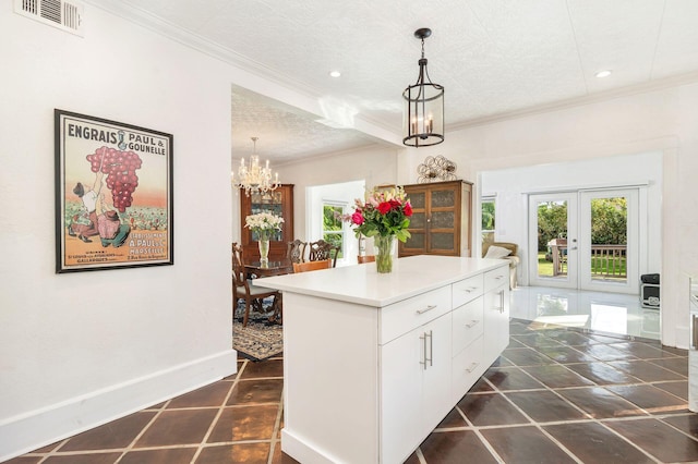 kitchen with visible vents, white cabinets, light countertops, pendant lighting, and a notable chandelier