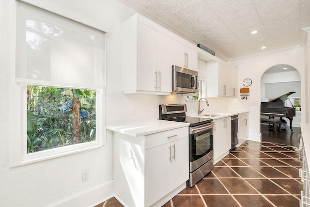 kitchen with tasteful backsplash, light countertops, appliances with stainless steel finishes, white cabinets, and a sink