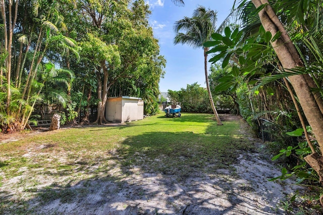 view of yard featuring a storage shed, an outdoor structure, and fence