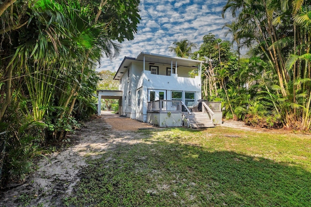 rear view of house with a wooden deck, a carport, and a yard