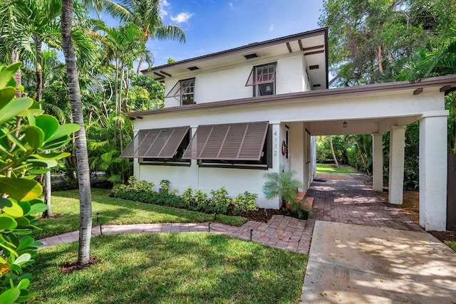 view of front facade with a front lawn, roof mounted solar panels, and stucco siding