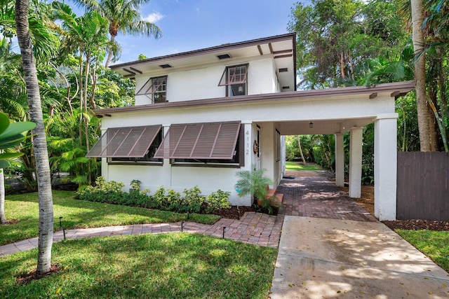 view of front facade featuring roof mounted solar panels, a front lawn, decorative driveway, and stucco siding