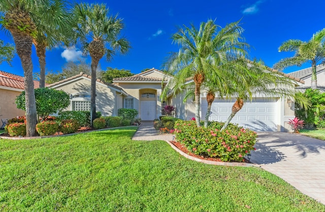 mediterranean / spanish house with a garage, a tiled roof, decorative driveway, stucco siding, and a front yard