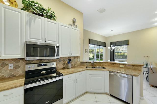 kitchen featuring tasteful backsplash, appliances with stainless steel finishes, light tile patterned flooring, a sink, and a peninsula