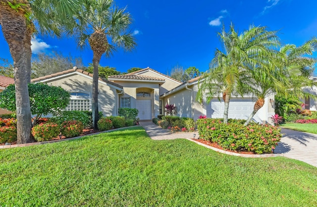 mediterranean / spanish home featuring decorative driveway, a tile roof, stucco siding, an attached garage, and a front lawn