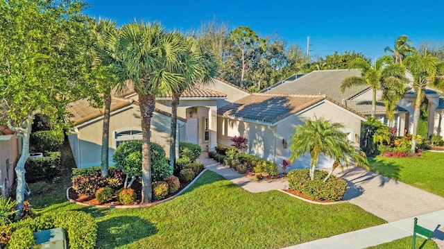 mediterranean / spanish home featuring a garage, a tiled roof, decorative driveway, a front yard, and stucco siding