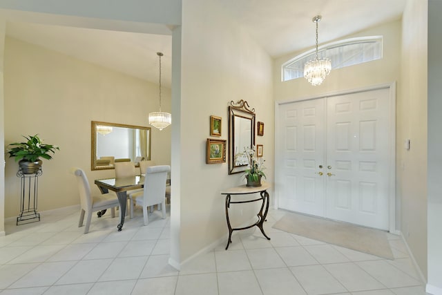 foyer entrance with baseboards, light tile patterned flooring, a towering ceiling, and a notable chandelier