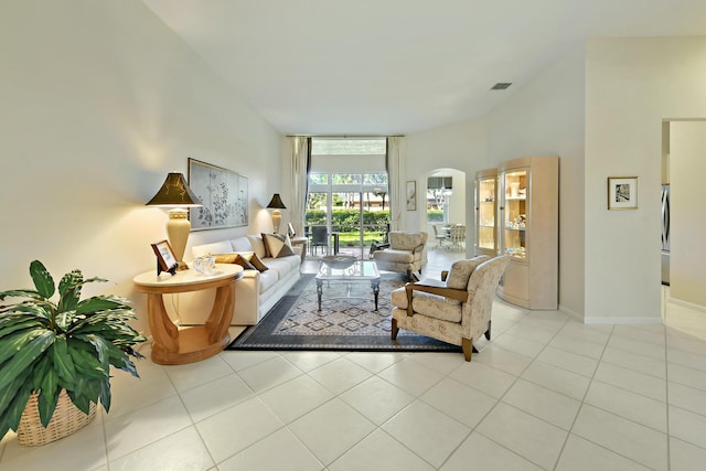 living area featuring arched walkways, baseboards, and tile patterned floors