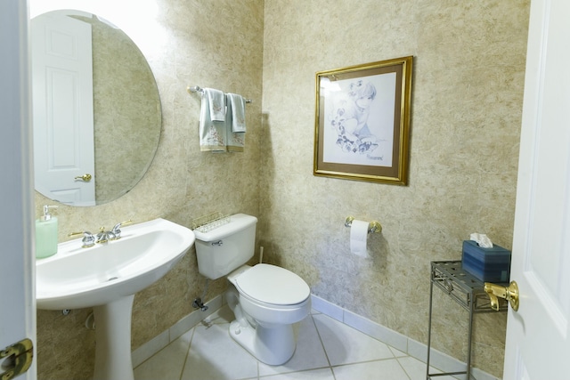 half bathroom featuring tile patterned flooring, toilet, and baseboards