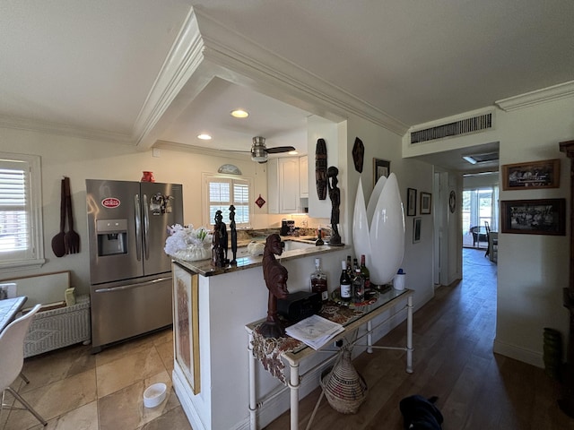 kitchen with visible vents, white cabinets, stainless steel fridge with ice dispenser, a peninsula, and crown molding